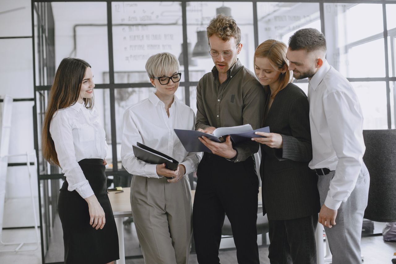Home A diverse group of professionals collaborating and discussing documents in a modern office space.